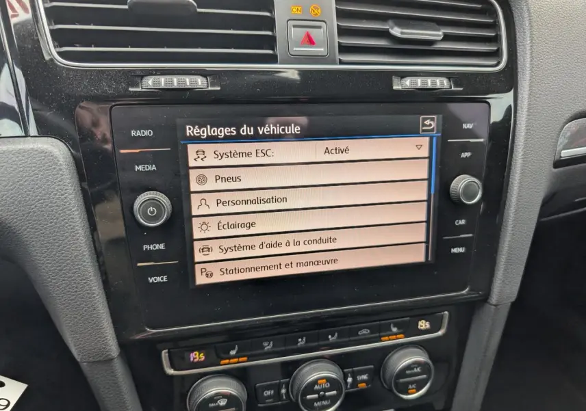 Écran central tactile affichant les réglages du véhicule dans l'habitacle noir d'une Volkswagen Golf VII R 2017.