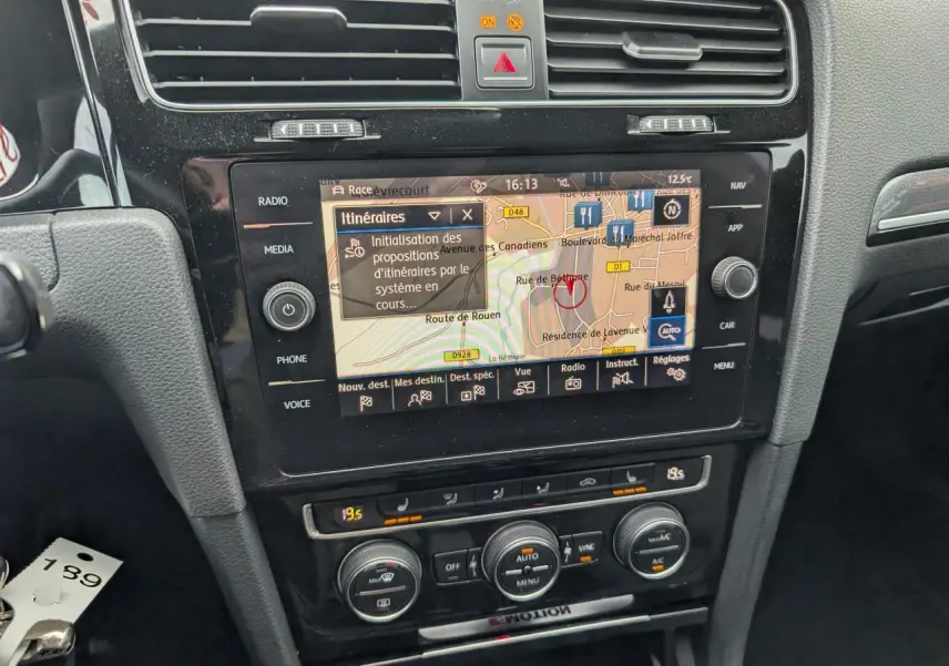 Vue rapprochée de la console centrale noire de la Volkswagen Golf R 2017 avec écran de navigation et commandes de climatisation.