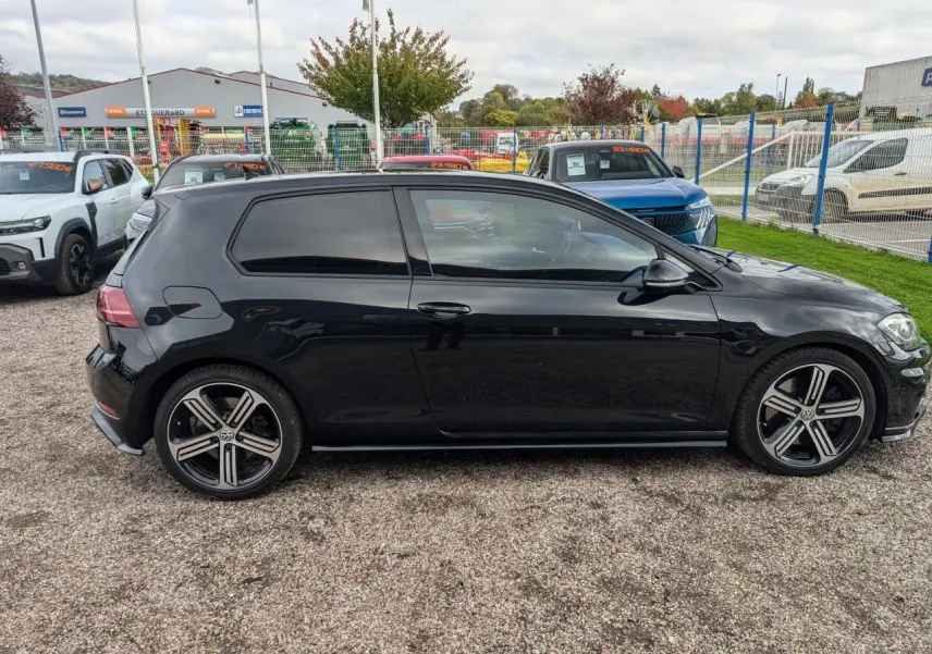 Profil droit d'une Volkswagen Golf noire 2017 avec jantes alliage 5 branches et vitres teintées.
