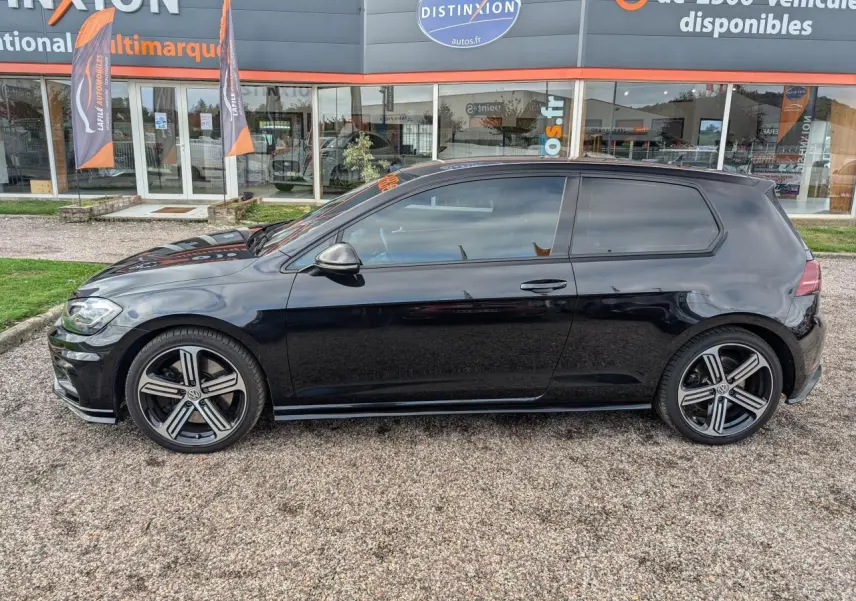 Profil côté gauche d'une Volkswagen Golf noire 2017 avec jantes alliage et vitres arrière teintées devant un showroom