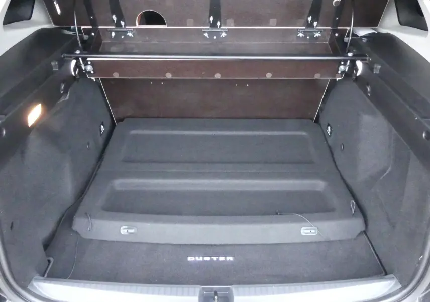 Coffre ouvert du Dacia Duster noir 2023, vue arrière montrant le tapis avec logo Duster et cache-bagages intégré.