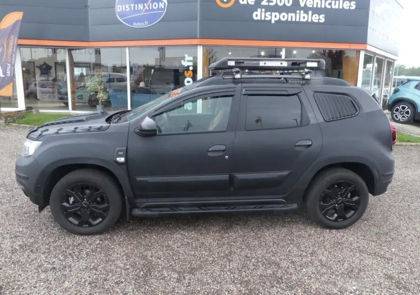 Profil côté gauche d'un Dacia Duster noir 2023 avec galerie de toit, marchepied et jantes alliage noires.