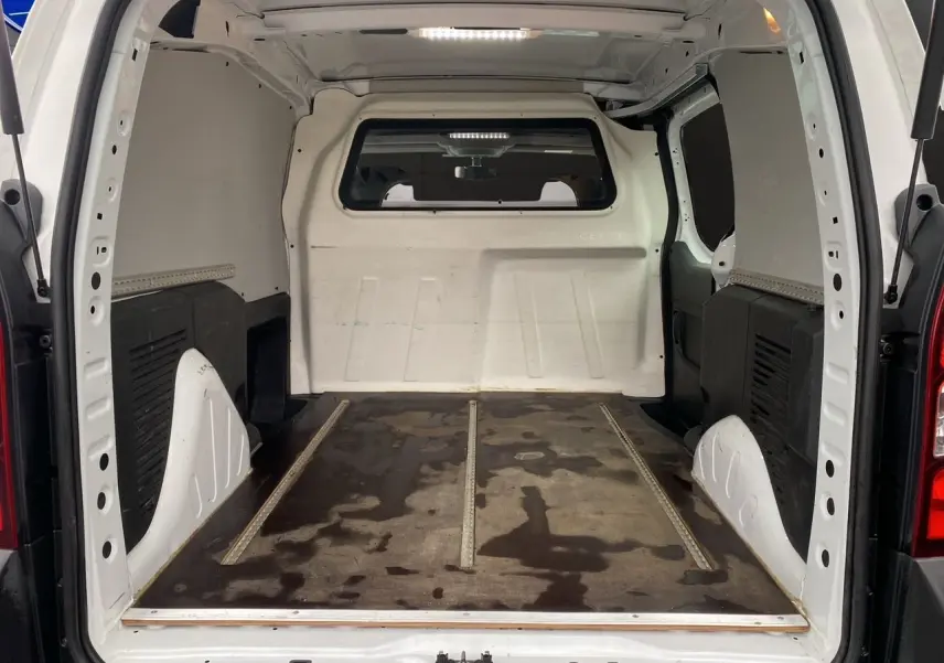 Vue intérieure arrière du Citroën Berlingo blanc 2018, montrant l’espace de chargement vide avec sol usé et parois blanches.