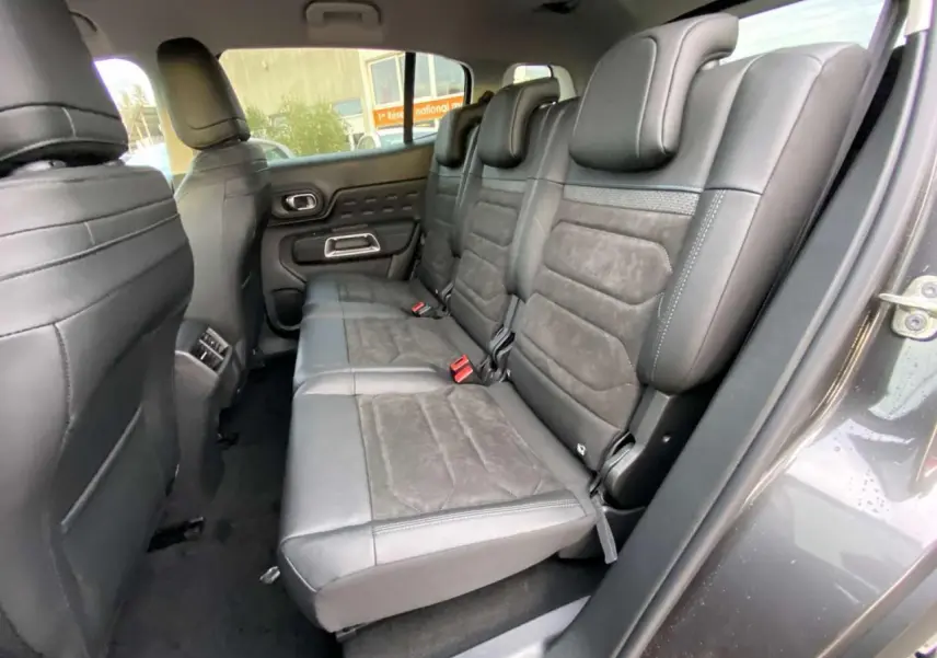 Vue intérieure côté droit sur la banquette arrière en cuir noir du Citroën C5 Aircross gris platinium, avec appuie-têtes et ceintures visibles.