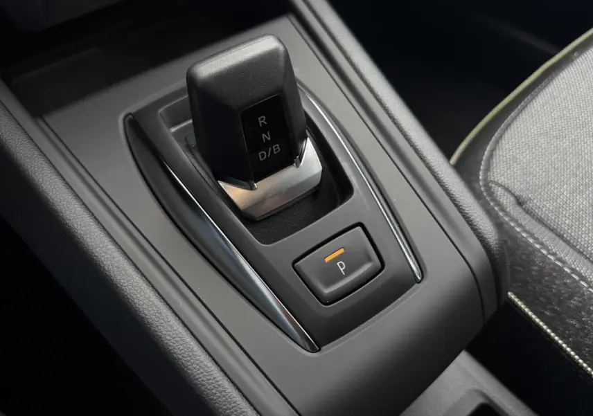 Gros plan sur la commande de boîte automatique noire du Renault Captur gris Rafale, avec bouton de parking éclairé.