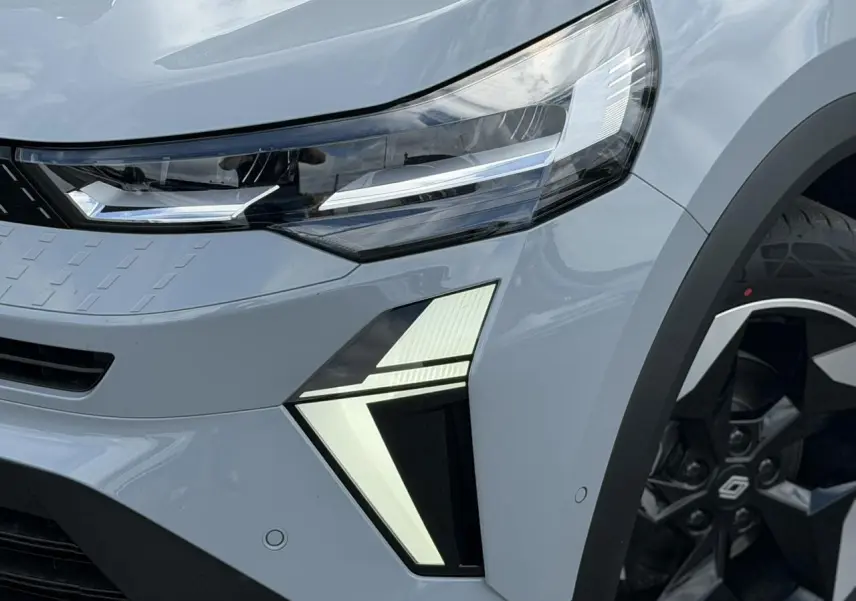 Gros plan sur l'avant droit gris Rafale du Renault Captur 2026, mettant en valeur le phare LED et la jante aluminium noire.