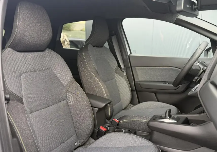 Vue intérieure côté droit du Renault Captur 2026, sièges tissu gris avec surpiqûres contrastées et console centrale.