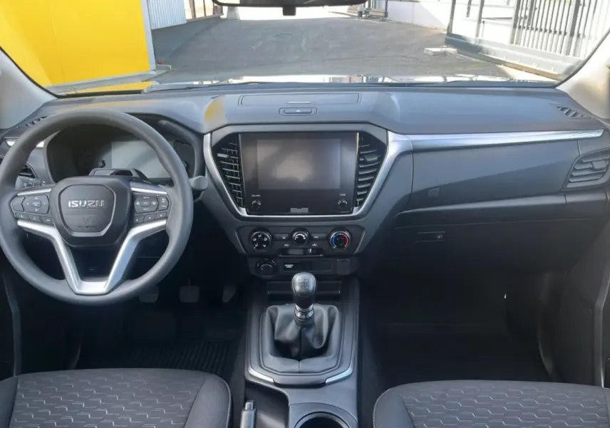 Vue intérieure avant de l'Isuzu D-MAX 2.2 TD 164 Space Evolution, tableau de bord gris avec volant multifonctions et boîte manuelle.