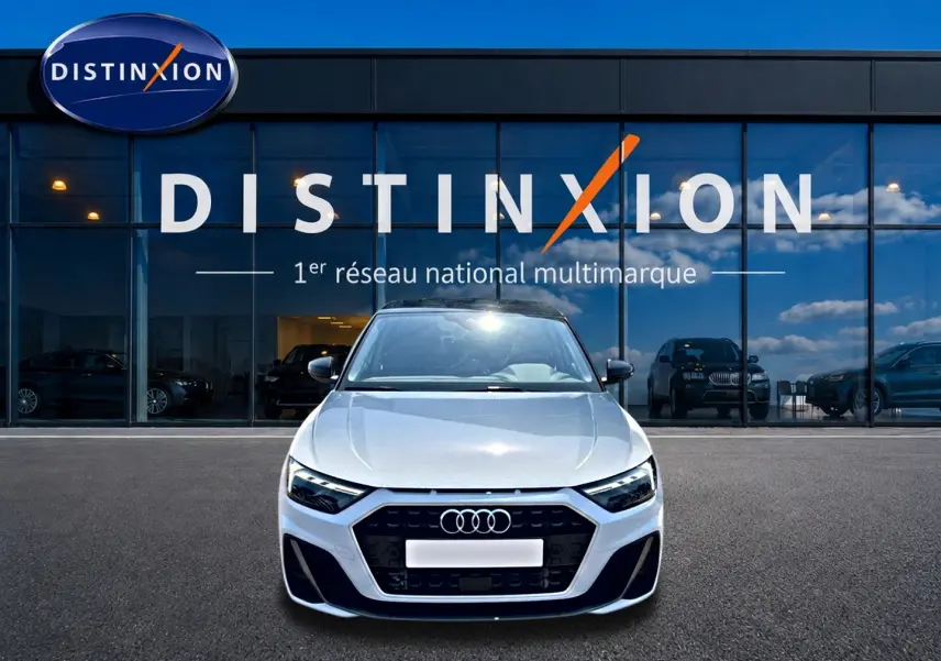 Audi A1 Sportback blanc et noir vue de face, avec calandre noire et logo Audi visible devant un showroom Distinxion.