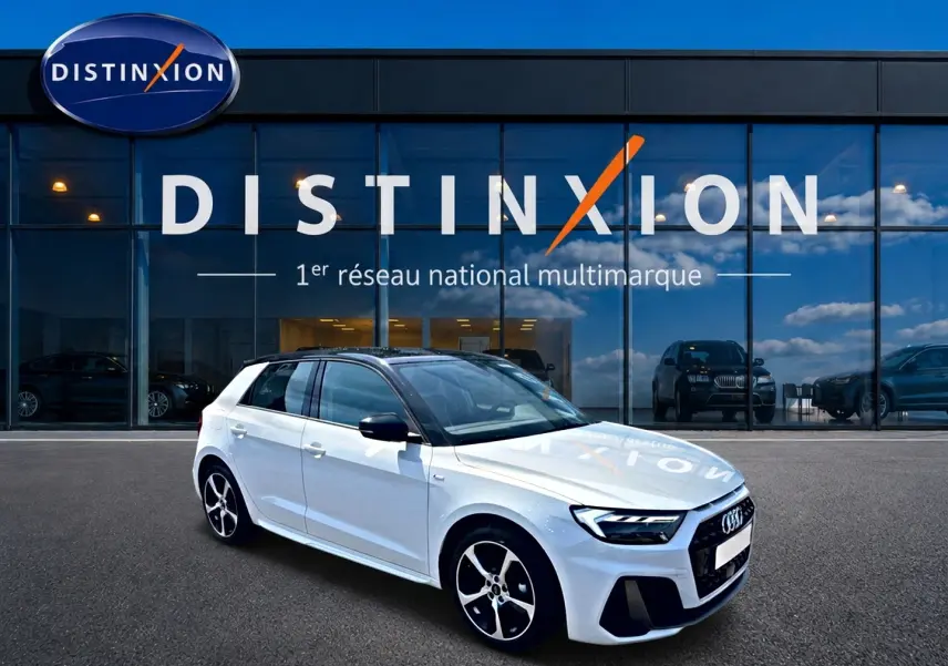 Audi A1 Sportback blanc et noir vue 3/4 avant droit devant une vitrine avec logo Distinxion.