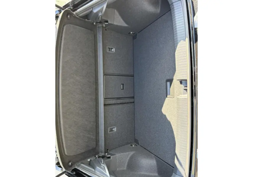 Coffre ouvert du Volkswagen T-Roc noir Grenadilla, montrant l'espace de rangement et la finition intérieure grise.