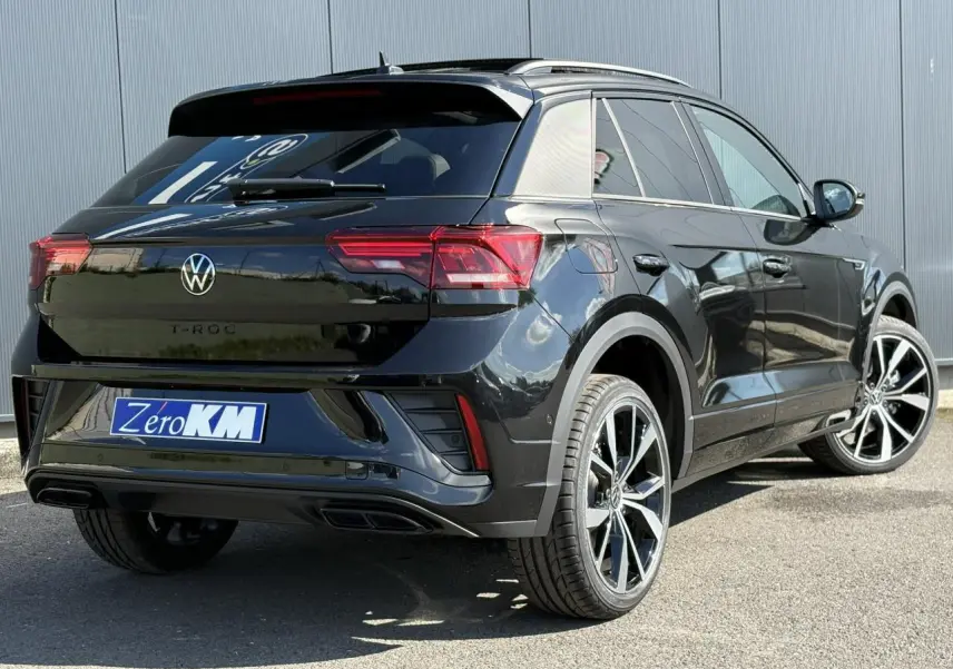 Volkswagen T-Roc noir Grenadilla en 3/4 arrière droit, jantes alliage 19 pouces et toit ouvrant visible.