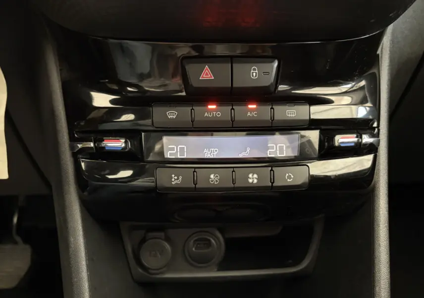 Panneau de commande de la climatisation digitale noir brillant dans l'habitacle d'une Peugeot 2008 rouge.