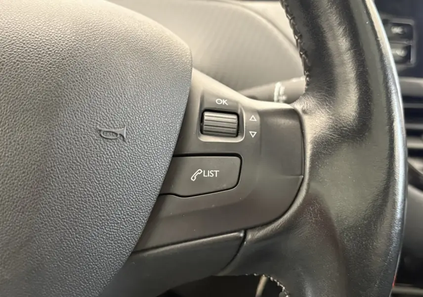 Gros plan sur le volant cuir noir du Peugeot 2008 Puretech 110 S&S EAT6 Allure de 2019, avec commandes intégrées.