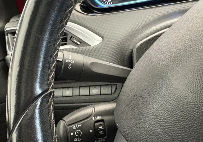 Gros plan sur le volant cuir noir de la Peugeot 2008, avec commandes de régulateur de vitesse visibles.
