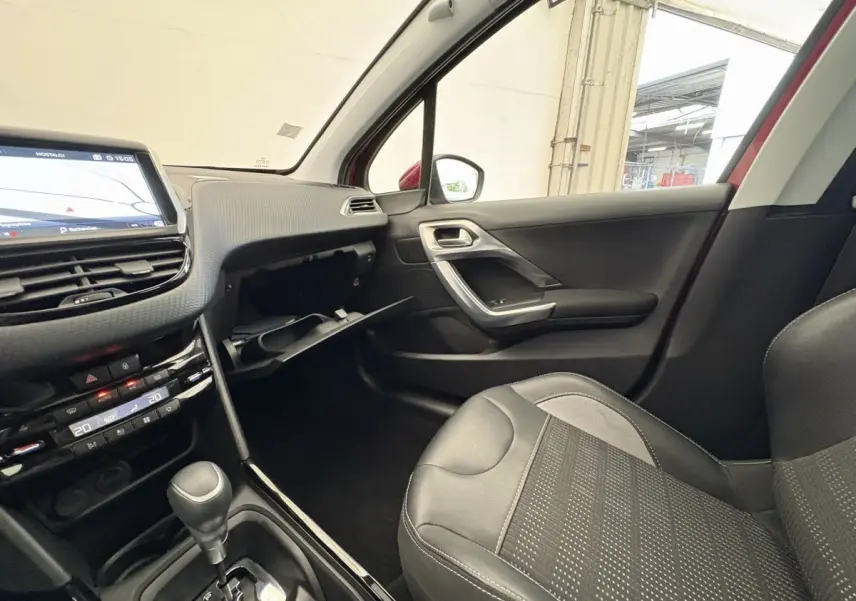 Intérieur côté passager du Peugeot 2008 rouge 2019, avec tableau de bord tactile et siège en cuir noir.