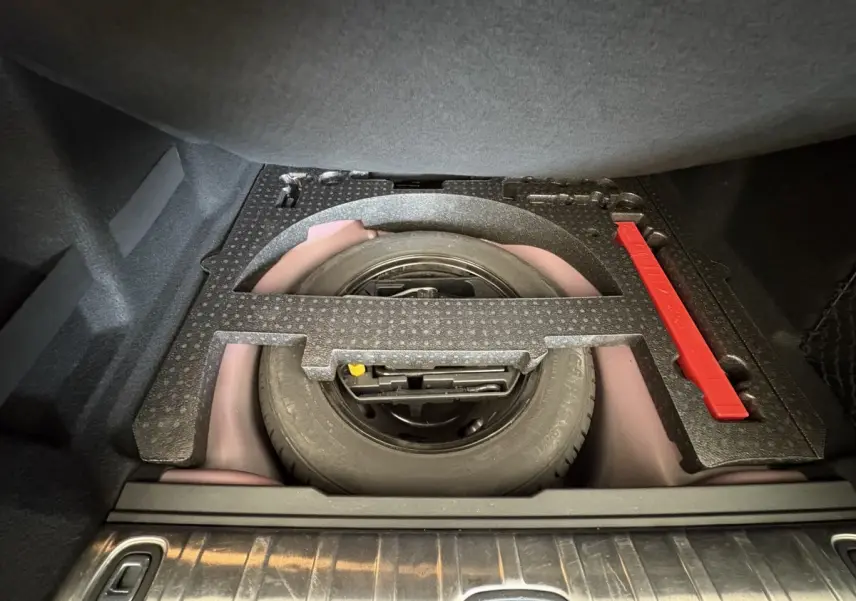 Vue plongeante sur la roue de secours et le rangement sous tablette du coffre du Peugeot 2008 rouge 2019.