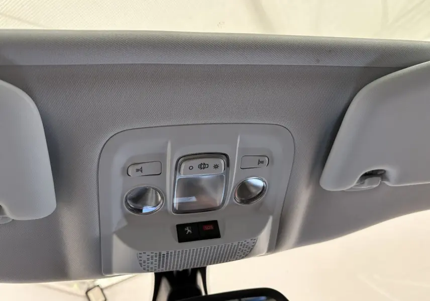 Vue en gros plan du plafonnier gris clair avec commandes d'éclairage et bouton SOS dans un Peugeot 2008 rouge