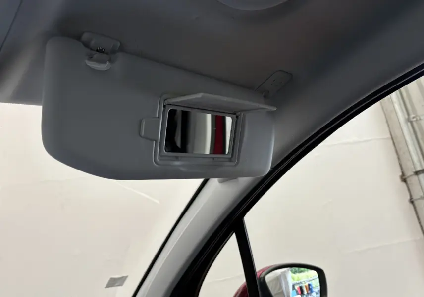 Miroir de courtoisie ouvert sur pare-soleil côté conducteur dans l'habitacle d'un Peugeot 2008 rouge 2019.