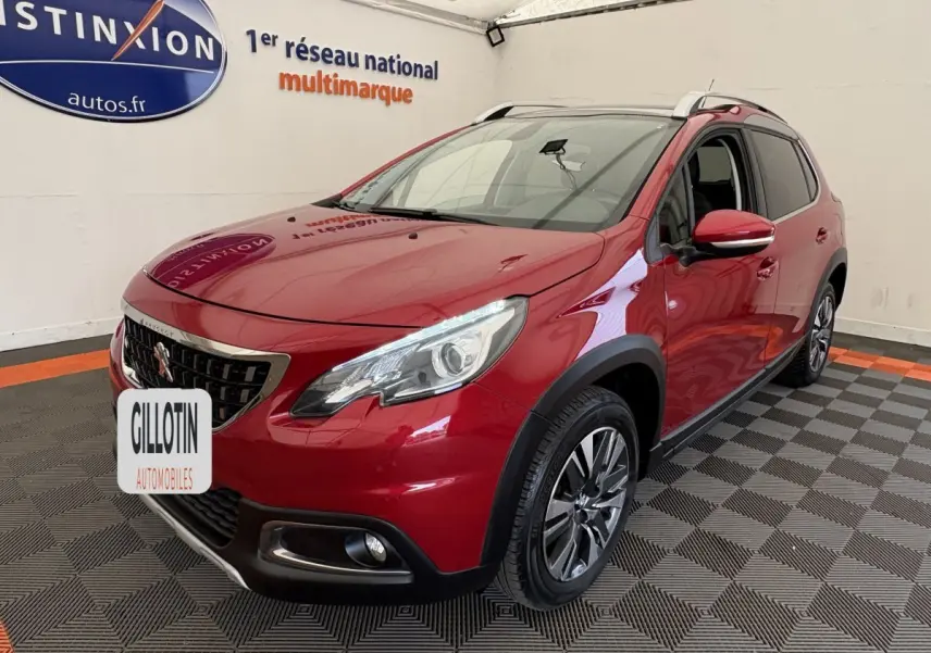 Peugeot 2008 rouge vue 3/4 avant droit en intérieur, avec phares LED et jantes alliage distinctives.