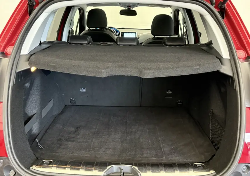 Coffre ouvert d'un Peugeot 2008 rouge 2019, vue arrière montrant l'espace de chargement avec tablette de protection.