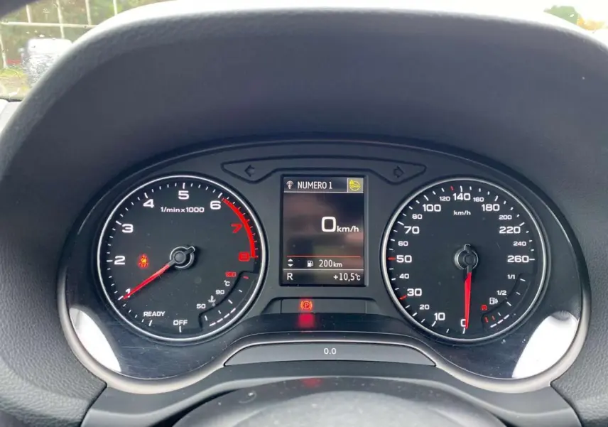 Vue rapprochée du combiné d'instruments Audi Q2 2023, affichage digital au centre, compte-tours et compteur de vitesse analogiques.