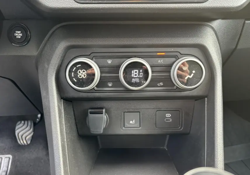 Vue rapprochée de la console centrale de la Dacia Sandero Stepway 2025, avec commandes de climatisation automatique et prises USB.