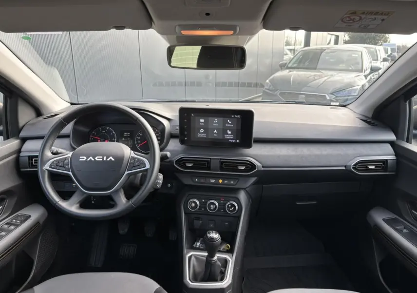 Vue intérieure avant du tableau de bord et volant de la Dacia Sandero Stepway Bleu Iron avec écran tactile et boîte manuelle.