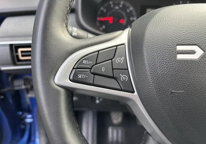 Gros plan sur le volant côté gauche du Dacia Sandero Stepway Bleu Iron 2025 avec commandes de régulateur de vitesse.