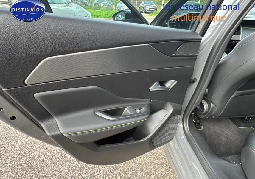 Gros plan sur la porte arrière gauche gris selenium de la Peugeot 308 SW Phev 225 GT avec garniture noire et surpiqûres vertes.