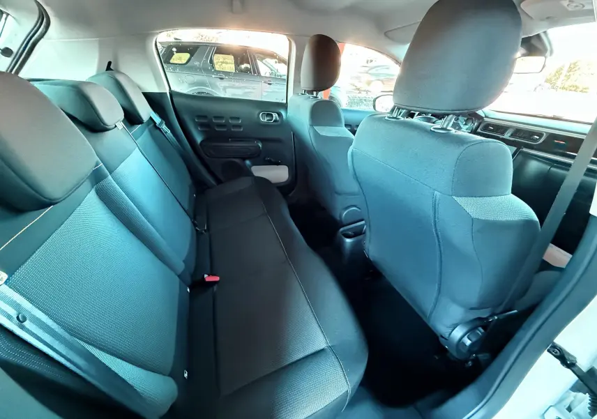Vue intérieure arrière de la Citroën C3 blanche de 2021, montrant les sièges arrière en tissu noir et gris.