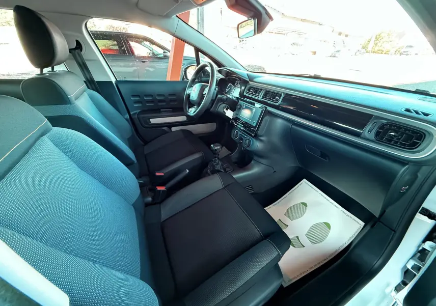 Intérieur de la Citroën C3 blanc vu côté passager, montrant sièges noirs et tableau de bord avec écran tactile central.