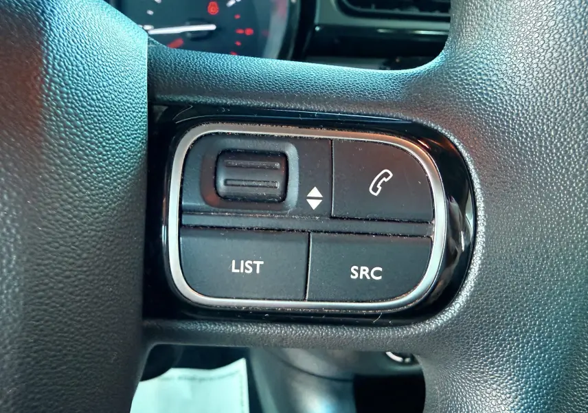 Gros plan sur les commandes gauche du volant d'une Citroën C3 blanche de 2021, boutons LIST et SRC visibles.
