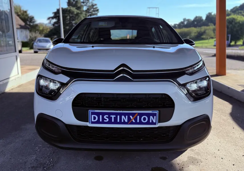 Vue frontale d'une Citroën C3 blanche de 2021 avec calandre noire et plaque Distinxion visible.