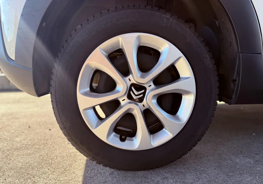 Gros plan sur la roue avant droite d'une Citroën C3 blanche avec jante alliage au design moderne.