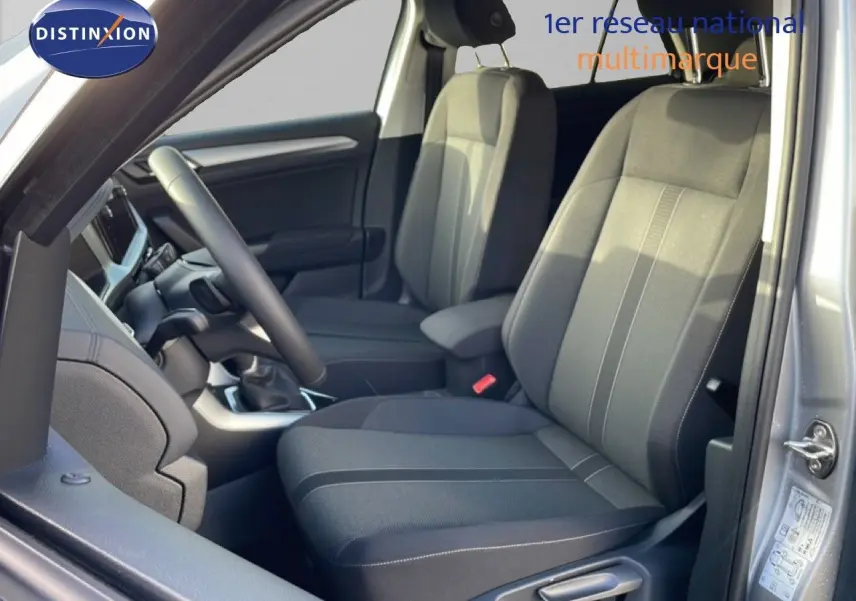 Vue intérieure côté conducteur du Volkswagen T-Roc gris pyrite métal, mettant en valeur les sièges tissu noir et le volant.