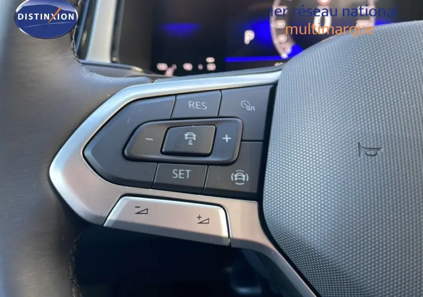 Gros plan sur les commandes au volant du Volkswagen T-Roc gris pyrite, mettant en valeur les boutons de régulateur de vitesse.