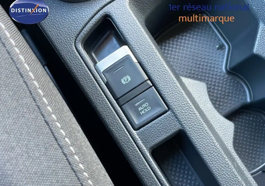 Gros plan sur la console centrale du Volkswagen T-Roc 2025, montrant les boutons de frein à main électrique et auto hold.