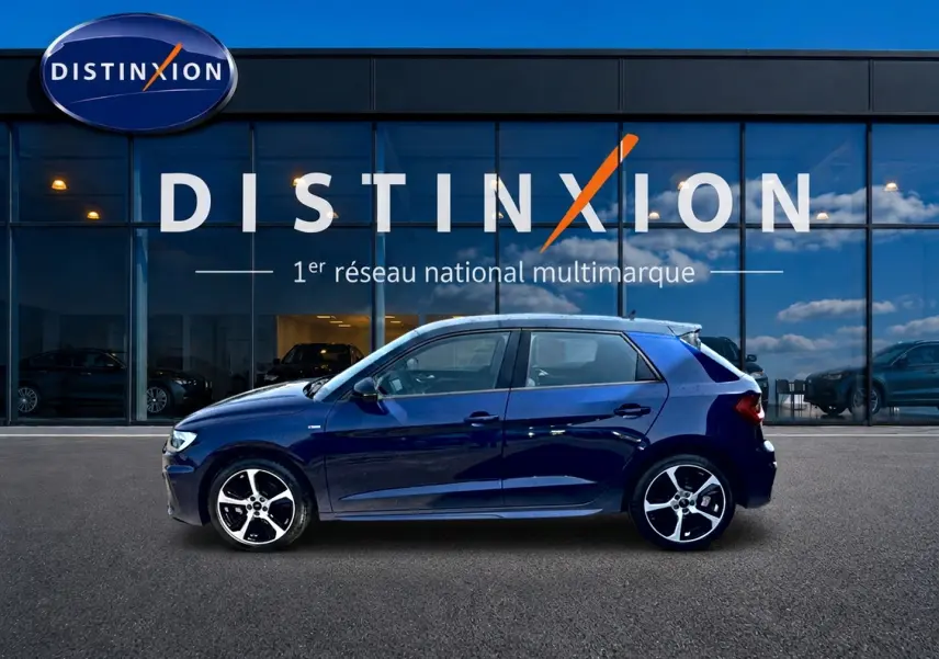 Profil droit de l'Audi A1 Sportback 30 TFSI bleu/noir avec jantes alu, devant une vitrine Distinxion.