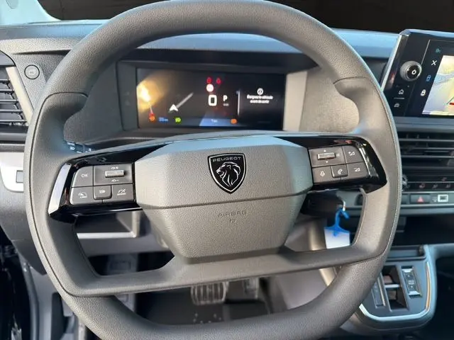 Vue rapprochée du volant noir du Peugeot Expert Fourgon 2025 avec commandes intégrées et tableau de bord numérique.