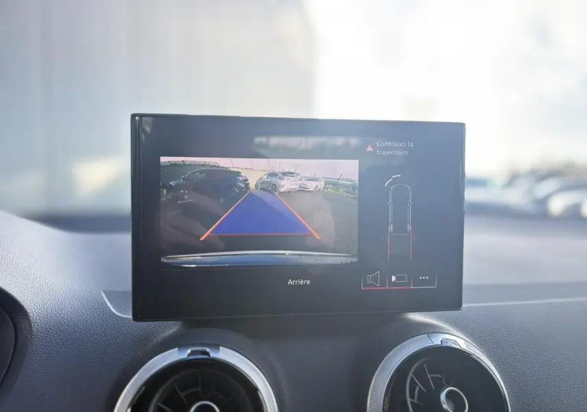 Écran central affichant la caméra de recul et l'aide au stationnement dans un Audi Q2 gris Daytona, vue intérieure.
