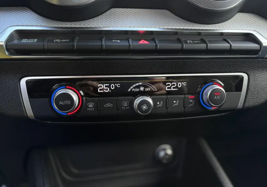 Vue rapprochée de la console centrale de l'Audi Q2 30 TDI S-Line 2025, affichant la climatisation automatique bi-zone.