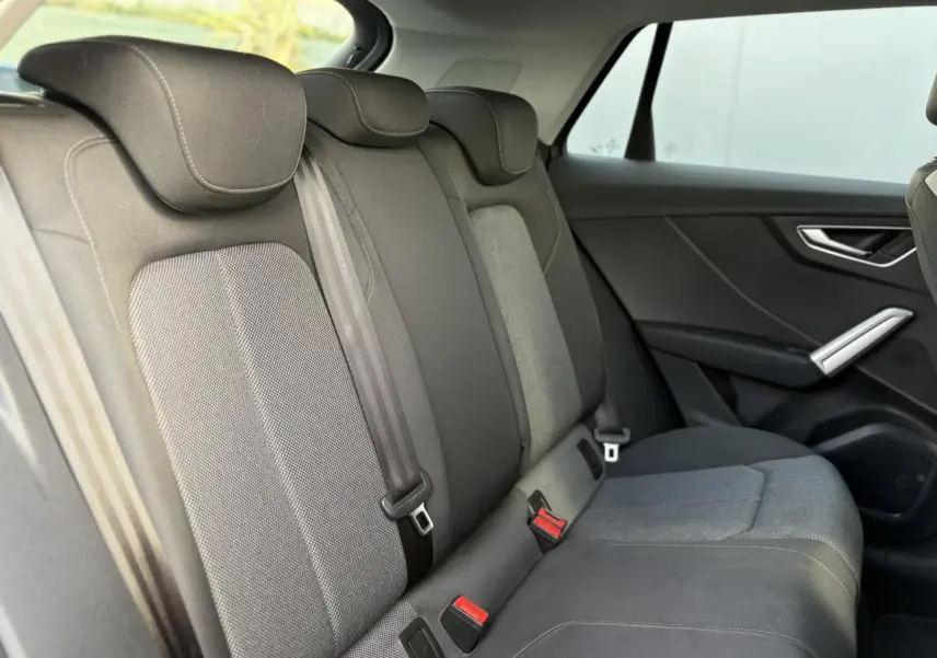 Vue intérieure côté droit des sièges arrière gris foncé de l'Audi Q2 30 TDI S-Line 2025 avec ceintures et appuie-têtes.