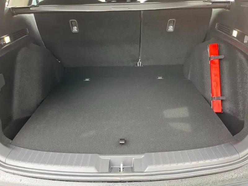 Coffre ouvert du Honda CR-V 2024 blanc nacré, vue intérieure montrant un espace de chargement propre avec triangle de sécurité rouge fixé à droite.