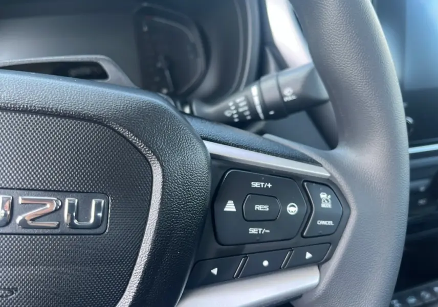 Gros plan sur le volant multifonctions noir de l'Isuzu D-MAX 2026 avec commandes de régulateur de vitesse.