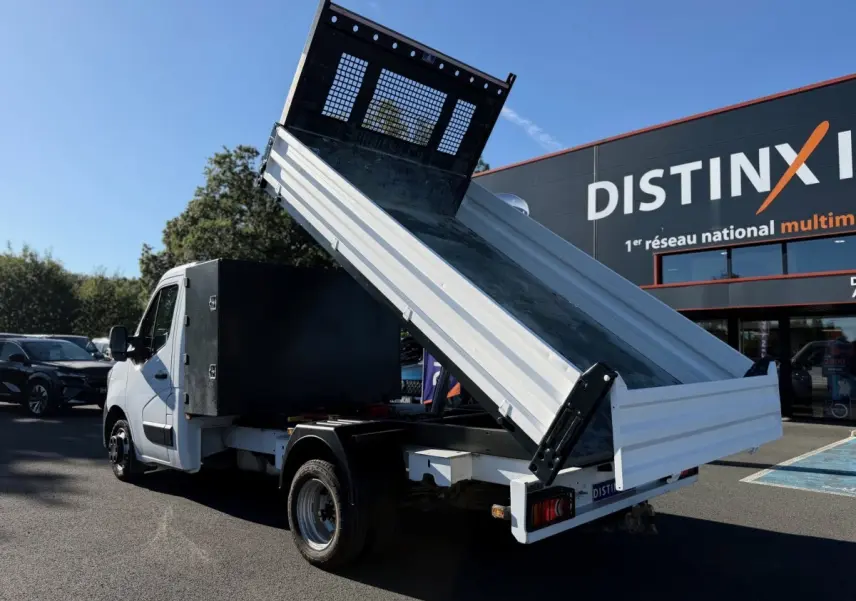Renault Master blanc vu en 3/4 arrière avec benne relevée et grand coffre noir sur parking extérieur.