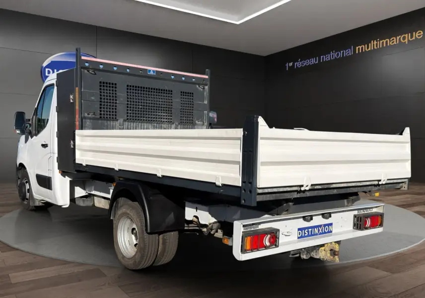 Renault Master blanc vue 3/4 arrière avec benne et ridelles blanches en intérieur showroom.