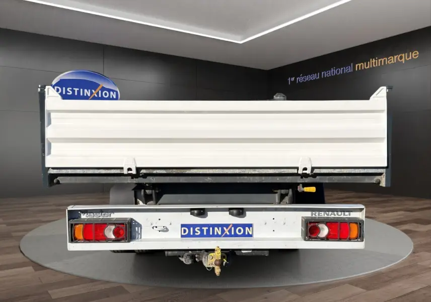 Vue arrière d’un utilitaire Renault Master blanc avec benne et attelage visible en intérieur showroom.