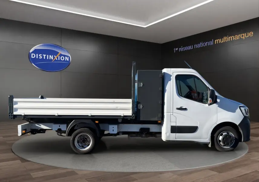 Renault Master blanc vu de profil côté droit, avec benne arrière et cabine simple dans un showroom.