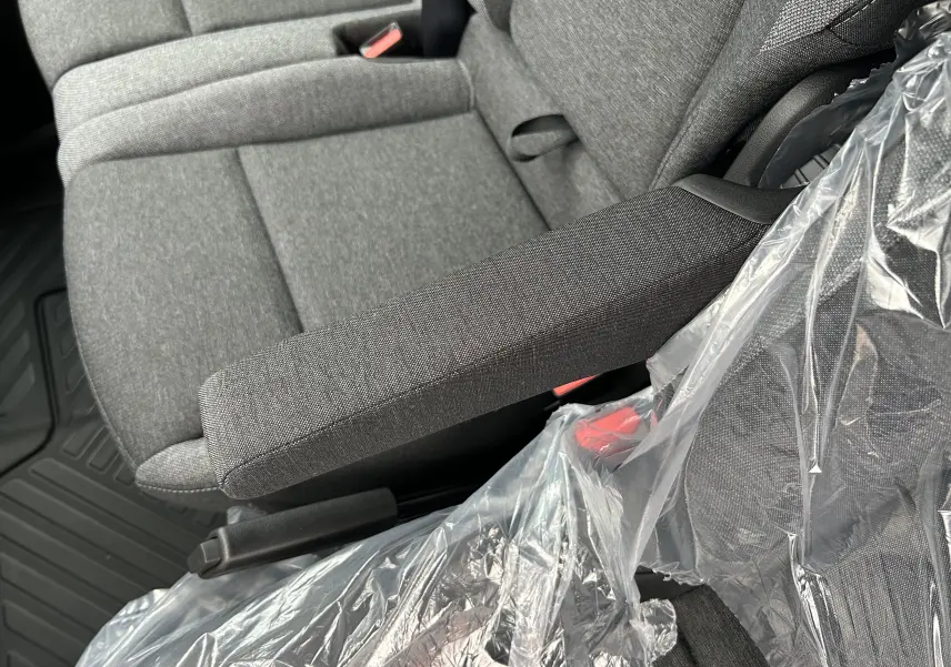 Gros plan sur la banquette passager avant grise du Renault Master 2026, avec accoudoir et protection plastique visible.